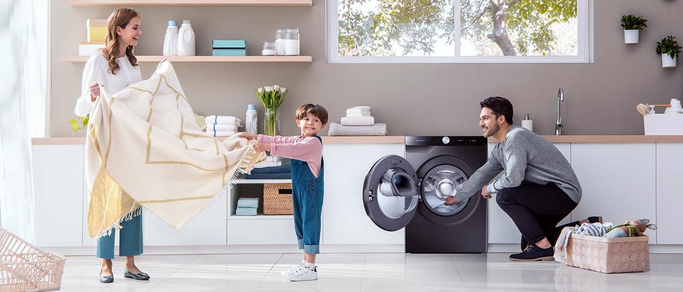 Mama, tata i dziecko wyjmują pranie z pralko - suszarki 