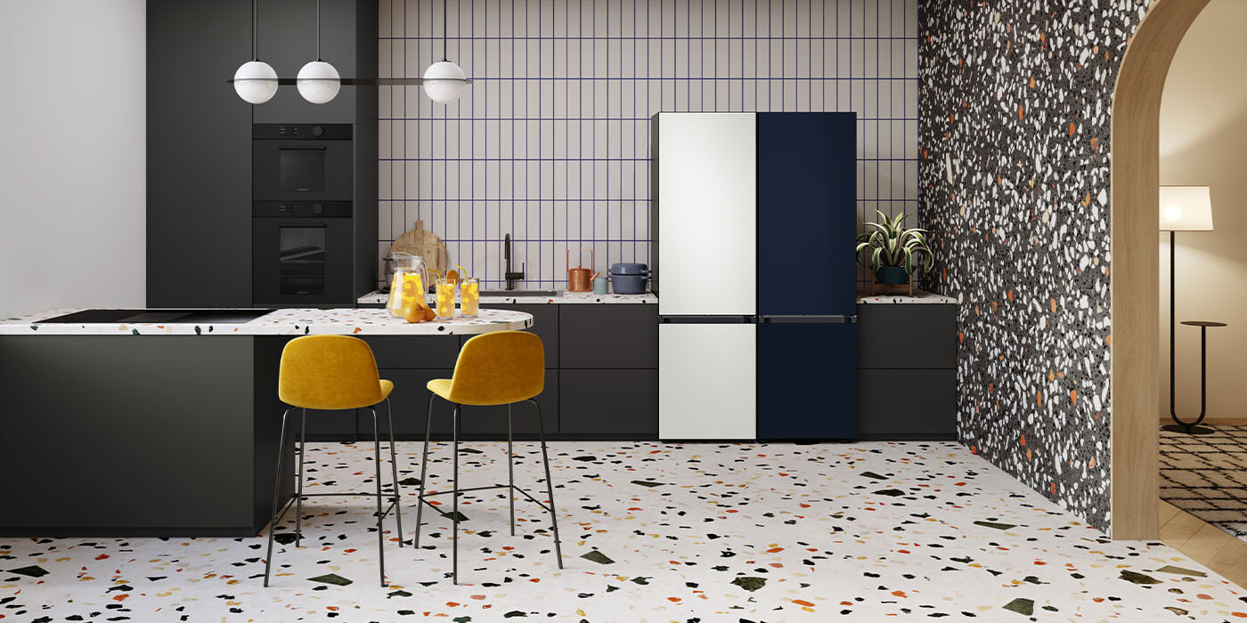 Ilustracja przedstawia kuchnię, w której panuje stylistyczna różnorodność. W pomieszczeniu ustawione są dwie lodówki Samsung z linii BESPOKE, które mają kolory alabastrowej bieli i satynowego grafitu.