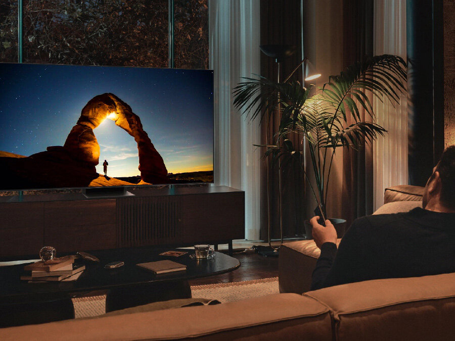 Mężczyzna przed telewizorem QLED w nocy. Ekran wyświetla obraz zoptymalizowany w Trybie Komfortu dla Oczu. Q70BATXXH