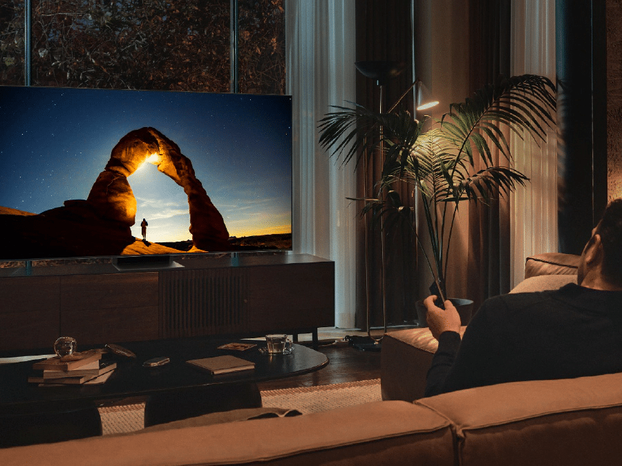 Mężczyzna przed telewizorem QLED w nocy. Ekran wyświetla obraz zoptymalizowany w Trybie Komfortu dla Oczu. Q80BATXXH