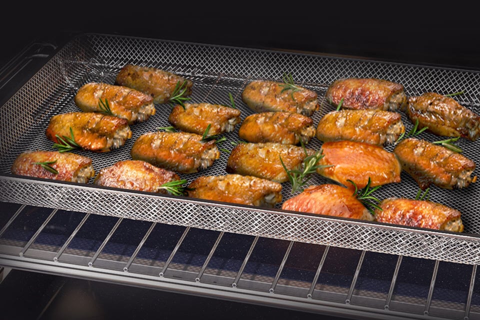 Rumiane kawałki kurczaka ułożone na tacy Air Fry ilustrują funkcję smażenia gorącym powietrzem