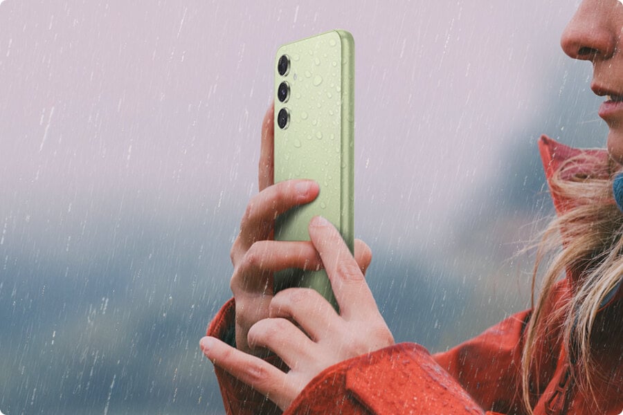 Kobieta robi sobie zdjęcie w deszczu z Galaxy A54 5G w kolorze limonkowym.