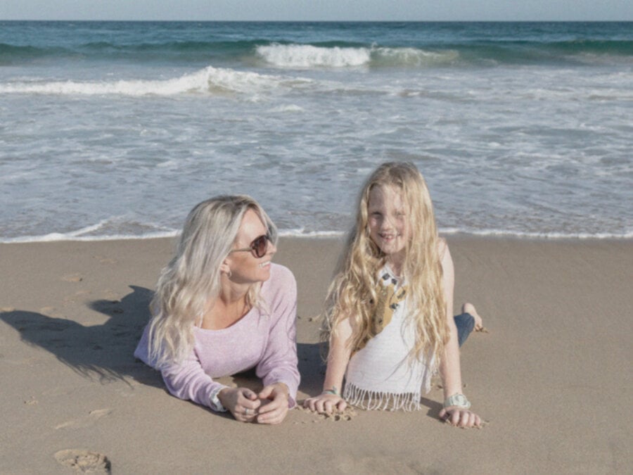W miarę przesuwania suwaka od lewej do prawej, aby zastosować Remaster GIF, ujęcie kobiety i młodej dziewczyny leżących na piaszczystej plaży staje się wyraźniejsze i jaśniejsze.