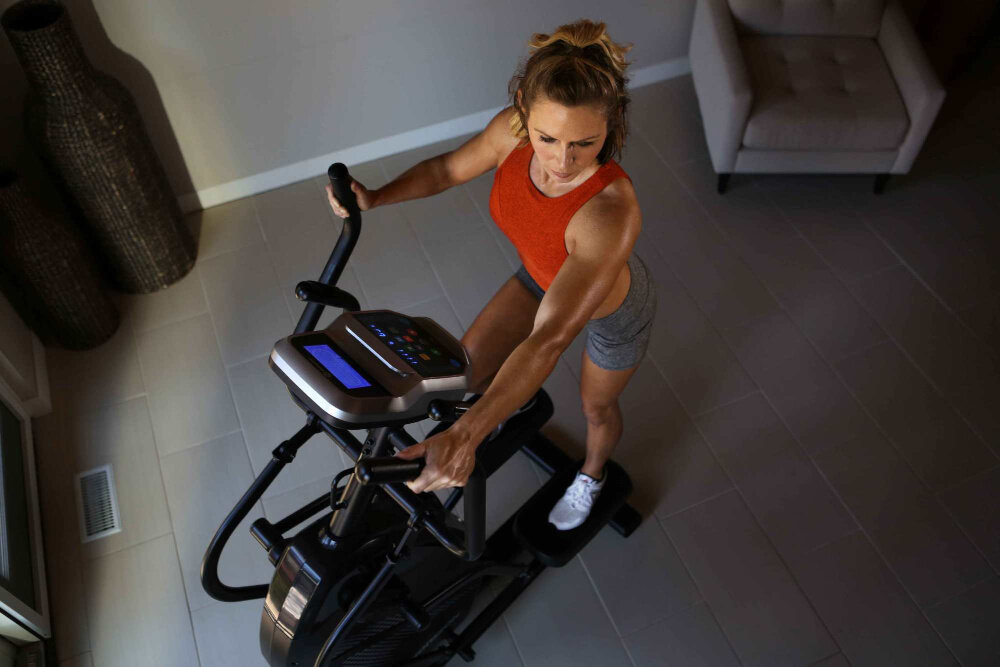 Orbitrek HORIZON FITNESS HT 5.0 Peak Trainer osoba ćwiczy na maszynie w pomieszczeniu widok z góry wbudowane głośniki słuchanie ulubionej muzyki regularne ćwiczenia osiąganie dobrych wyników