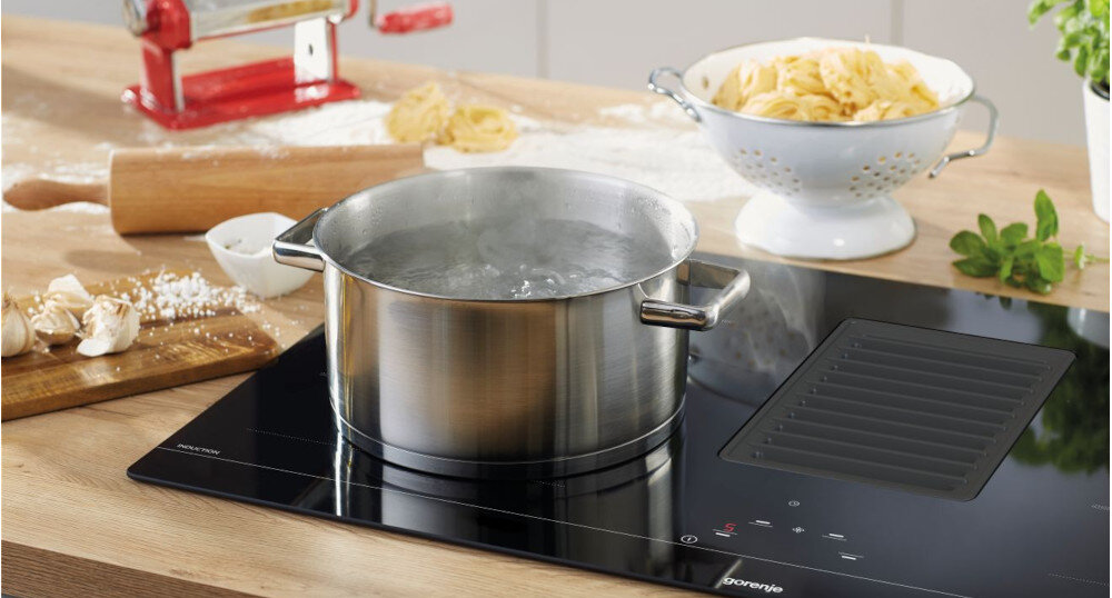 Płyta indukcyjna z okapem GORENJE HET949BSC zdjęcie lifestyle garnek z wodą gotowanie para sitko durszlak deska wałek PowerBoost Gotowanie z dodatkową mocą szybkie podgrzewanie oszczędność czasu wygoda efektywność