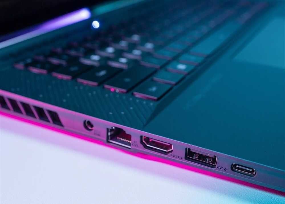 Zbliżenie na laptopa z fioletowym podświetleniem, ukazujące wszechstronne złącza na jego obudowie.  - Thunderbolt 4 USB Type-C 3.2 Gen. 2 DisplayPort USB-A 3.2 Gen. 2