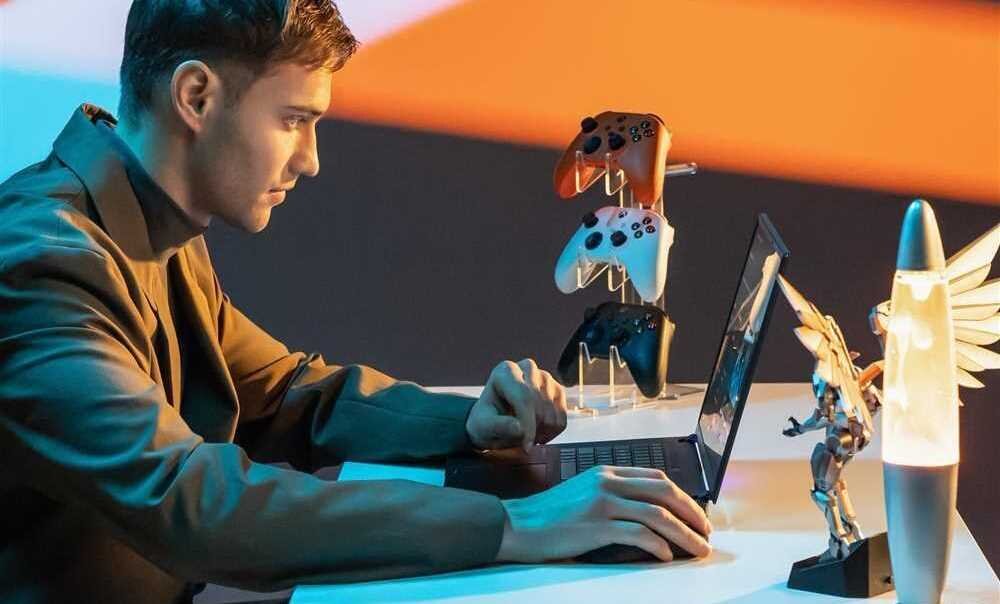 Mężczyzna siedzi przy biurku z laptopem GIGABYTE Aorus 16X i świecącą zabawką obok.  - Intel Core HX WQXGA 165 Hz AI NVIDIA GeForce RTX