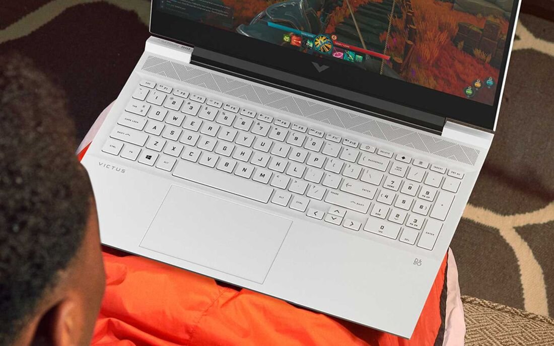 Laptop HP Victus 16 - Mężczyzna na kanapie korzysta z laptopa z podświetlaną klawiaturą. Podświetlana klawiatura Pełnowymiarowa klawiatura 