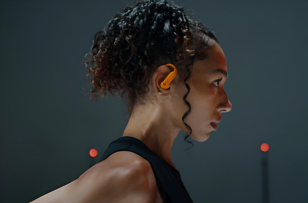 Słuchawki dokanałowe BEATS Powerbeats Pro 2 Elektryzujący pomarańczowy stworzone dla sportowców, kobieta ze słuchawką w uchu