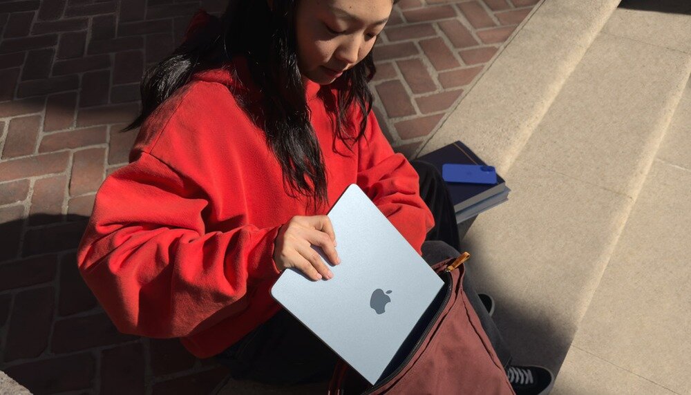 Жінка кладе ноутбук у сумку з MacBook Air