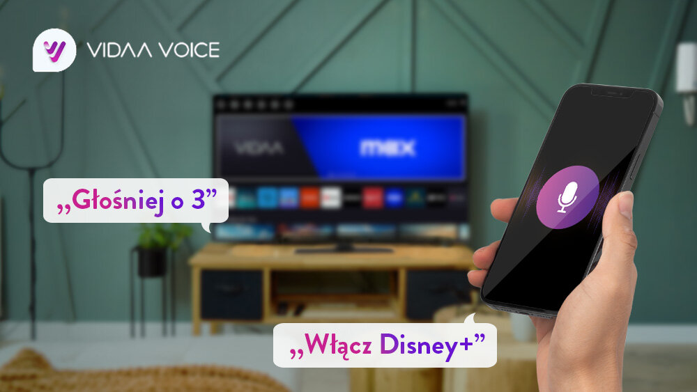 Telewizor JVC LT-55VDQ3500 - Steruj głosowo z VIDAA Voice, telewizor stojący w salonie na stoliku, na pierwszym planie jest ręka z telefonem przedstawiający sterowanie głosowe