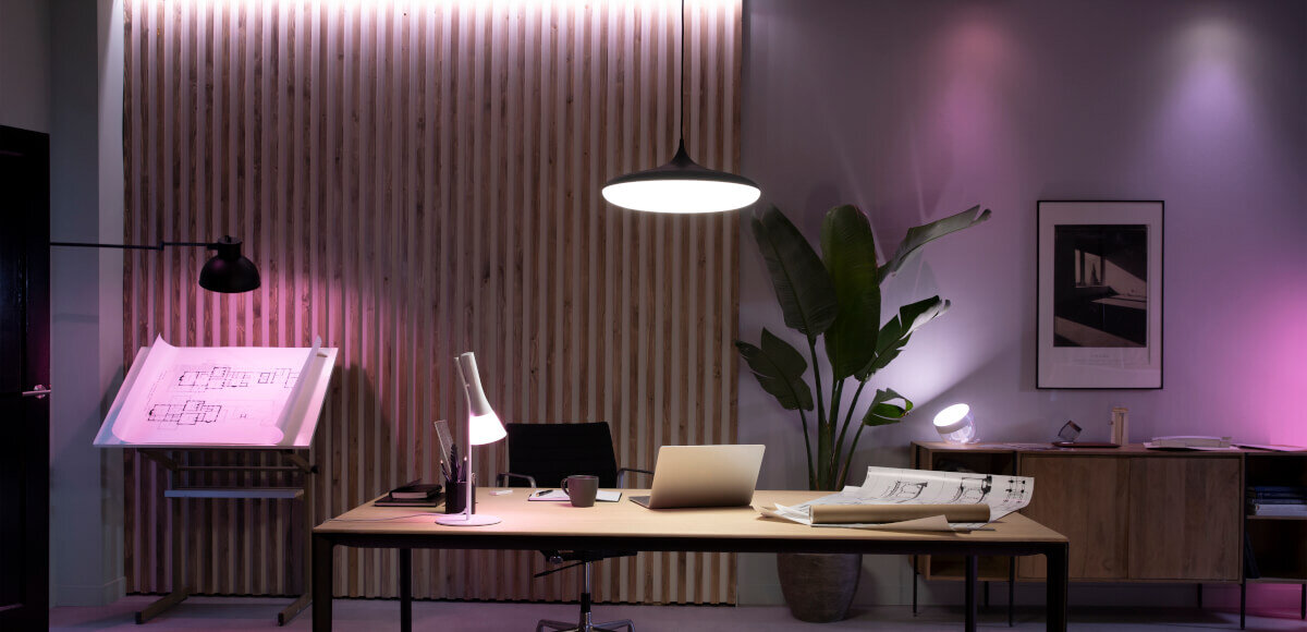 Taśma LED PHILIPS HUE 929003816902 3 m Bluetooth, inteligentne, aplikacje, partnerzy, kompatybilność, Lampka stoi na stole w pomieszczeniu gościnnym, w tle różne barwy światła
