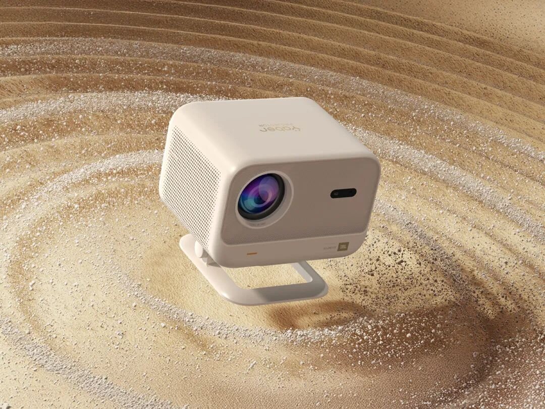 Projektor YABER L2 Plus - Brzmienie z kinowym rozmachem, Wbudowane głośniki JBL 8 W, Dolby Audio, projektor stojący na piaszczystym podłożu