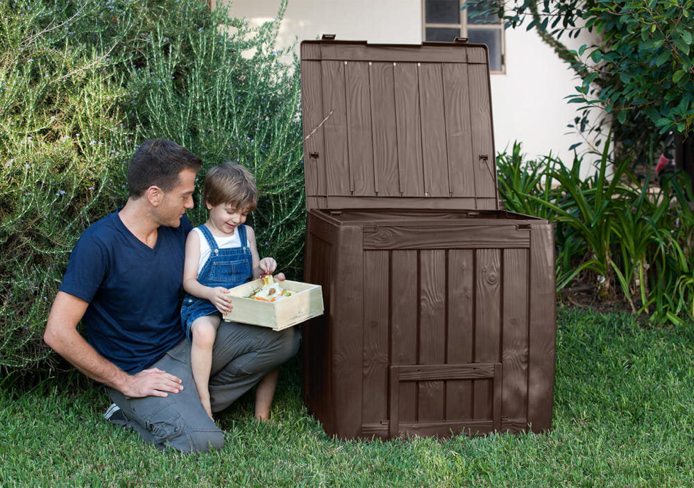 Kompostownik KETER Deco Composter 340L Brązowy kompostownik na trawie obok dwie osoby wkładające odpadki do wnętrza specjalne otwory wentylacyjne cyrkulacja powietrza pokrywa z wytrzymałym zamknięciem